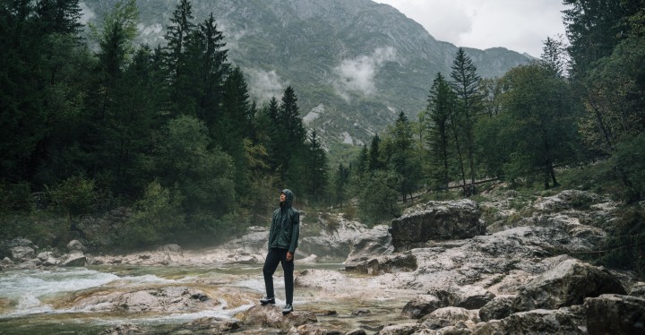 Man standing in outdoor clothing with a foggy, mountainous landscape