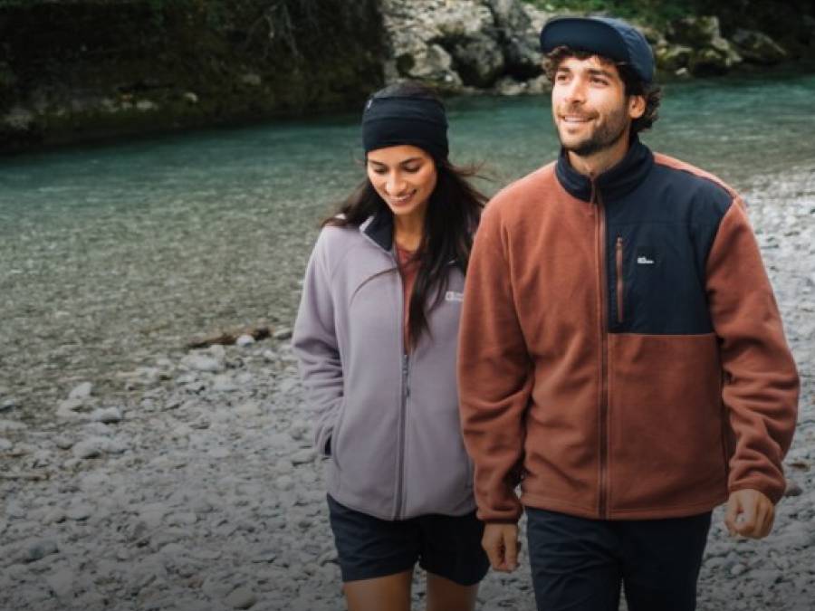 Two young adults in sporty fleece jackets in front of a lake